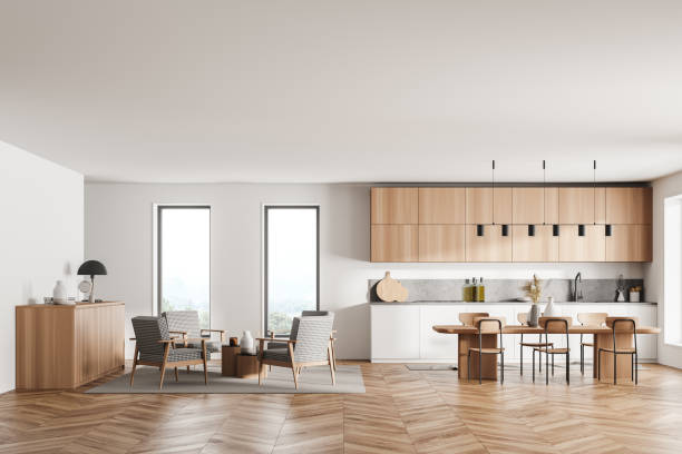 istock Stylish interior of bright and white modern kitchen room with dining table and chairs. Armchairs livingroom zone open space. 1319851329