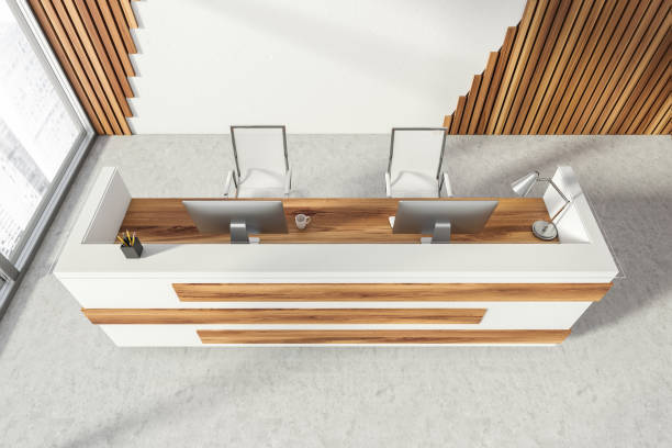 istock Empty office, wooden reception interior at white wall, 4 clocks on it. Panoramic window. Hotel check in desk. Top view. 1319852907