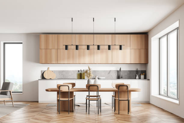 istock Stylish interior of bright and white modern kitchen room with dining table and chairs. Open space zone. Big window. 1319852990