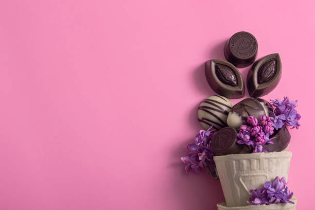 色の付いた背景にライラックで飾られたワッフルカップの創造的なアイスクリームチョコレートキャンディー。チョコレートの日 - tulipe cup ストックフォトと画像