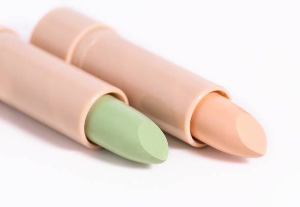 Foundation Green and beige face concealer isolated on white background. Preparing for face makeup. Two concealers in beige lids in the form of a lipstick. Skin color correcting concealers.