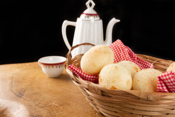 istock Brazilian cheese bread, checkered cloth basket with cheese breads on rustic wood with teapot and cup of coffee in the background, selective focus. 1319857342