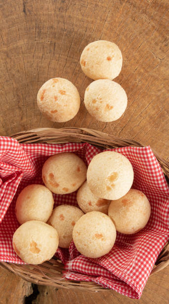 istock Brazilian cheese bread, basket with checkered cloth with cheese breads on rustic wood, top view. 1319857349