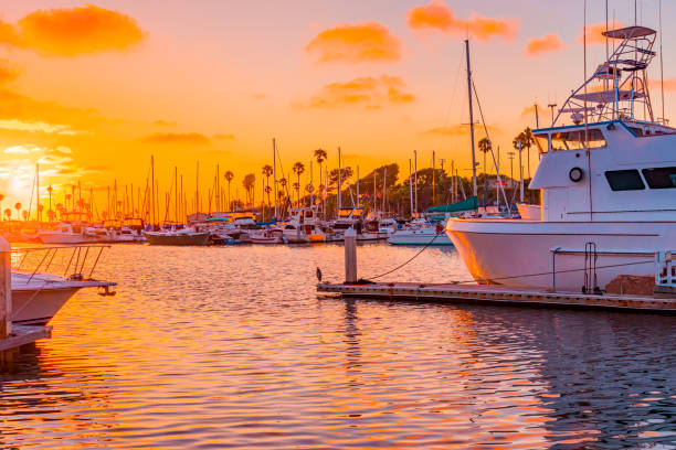 Sunset hits the Oceanside Harbor and glows on boats and water. Oranges and pinks highlight all the boats, water and sky in Oceanside Harbor, near Carlsbad, California in Southern California. Marina stock pictures, royalty-free photos & images