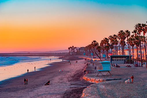 People sit and stroll at sunset on the beach in Oceanside, California. This is next to Carlsbad and San Diego.