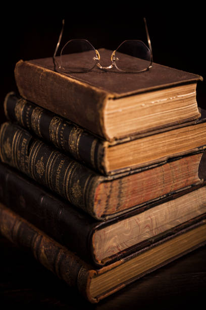 Stack of antique hardcover books with eyeglasses.