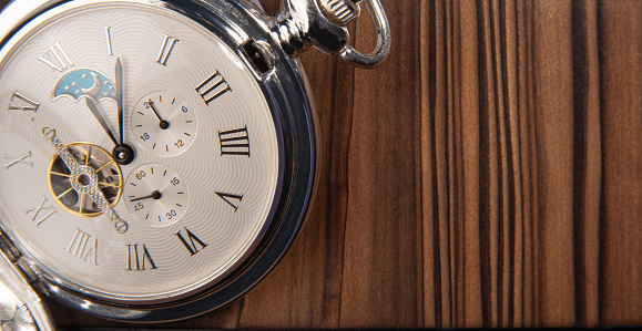 Antique clock, beautiful details of an old pocket watch on rustic wooden surface, selective focus.