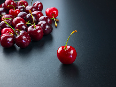 the best cherry choice among the group of cherries, the best fruit selection concept, red luxury fruit on black slate