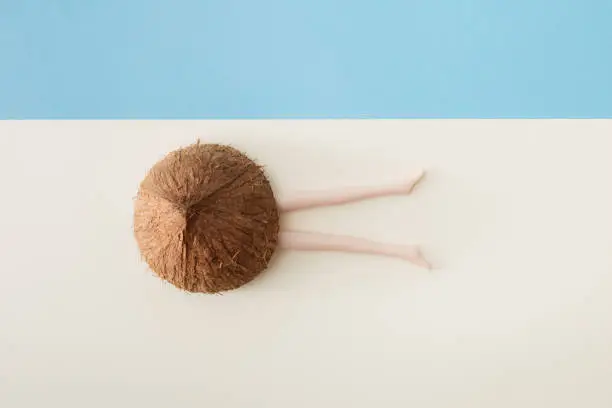 Coconut and plastic doll legs sticking out on a cream and blue background.