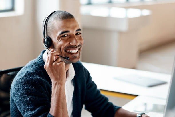 Portrait of a young businessman wearing a headset while working in an office Yes, I'm that IT guy! headset stock pictures, royalty-free photos & images
