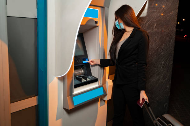 istock woman with face mask and bags using ATM 1319876246