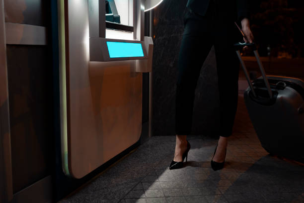 istock no face shot, woman standing with baggage next to ATM 1319876273