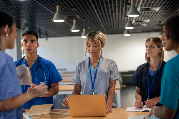 multiethnische gruppe von ärzten treffen sich, um eine patientenakte zu diskutieren - computer student mixed race person multi ethnic group stock-fotos und bilder