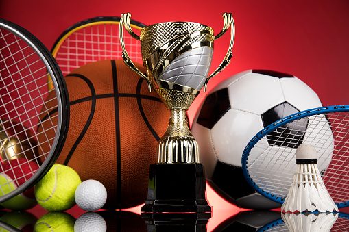 Close-up of trophy and sports equipment against red background.