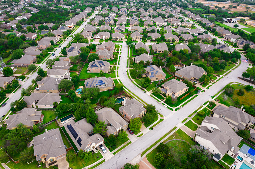 Perfect Suburb curved modern streets Row after row of thousands of nice large two story houses Aerial Drone view above Luxury living gated community Suburb in Austin Texas USA green summer landscape in Round Rock , TX