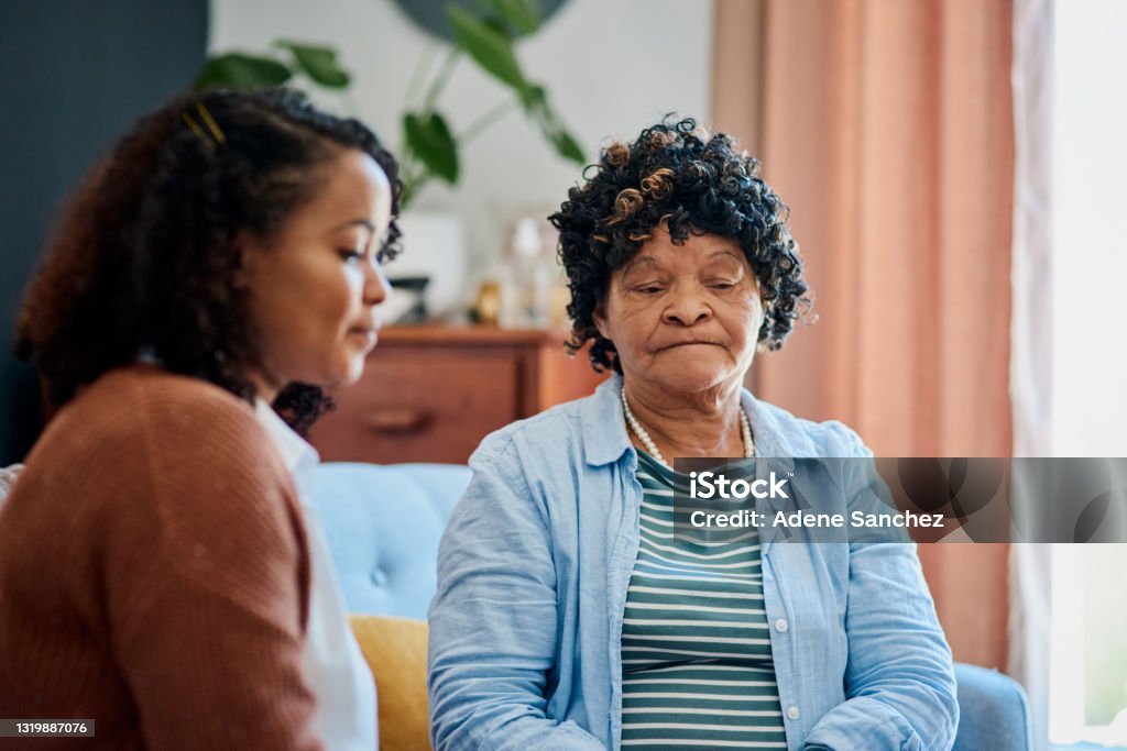 Shot of an elderly woman sitting with her daughter on the sofa at home and not talking If you can't talk to family, who can you talk to? Senior Adult Stock Photo