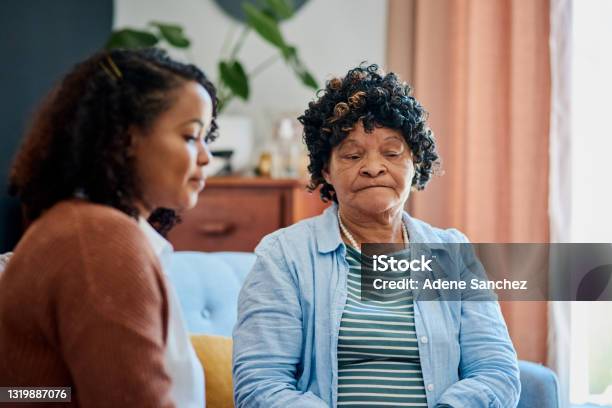 Shot Of An Elderly Woman Sitting With Her Daughter On The Sofa At Home And Not Talking Stock Photo - Download Image Now