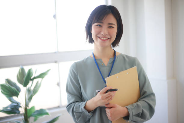 バインダーを持つ女性従業員 - 日本人　笑顔 ストックフォトと画像