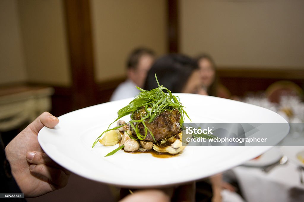 Serving meal Waiter serving tarragon crusted beef tenderloin, gnocchi,mushrooms,artichokes, canon 1Ds mark III Edible Mushroom Stock Photo