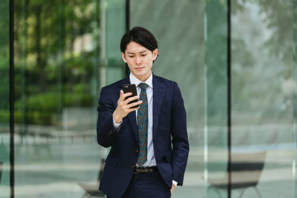 若い男性が仕事に来る - iot /スマートフォンでビジネスイメージ - スマホ 日本人 ストックフォトと画像