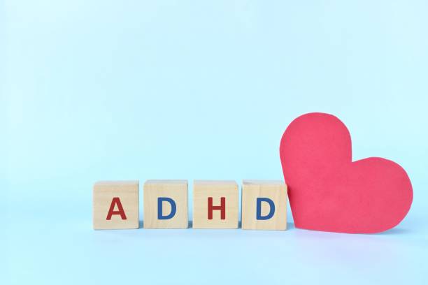istock Love and support kids with ADHD or attention deficit hyperactivity disorder concept. ADHD letters on wooden blocks beside a red heart shape with copy space. 1319891421