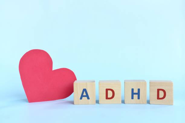 istock Love and support kids with ADHD or attention deficit hyperactivity disorder concept. ADHD letters on wooden blocks beside a red heart shape with copy space. 1319891425