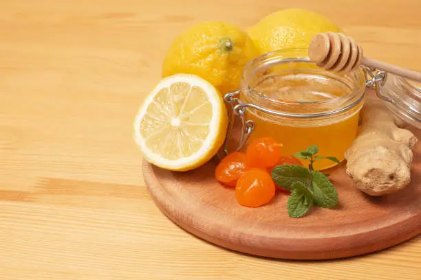 Ginger root, mint, lemon and liquid honey in honey-jar. Wooden background. Healthy food. Selective focus. High quality photo