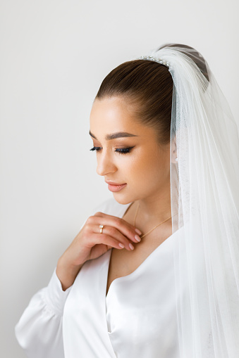 Morning of the bride in a white robe and a veil in the room