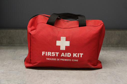 Home First Aid Kit for use around the house or as a small office first aid kit. On counter, red with white cross. First aid kit stock photo.