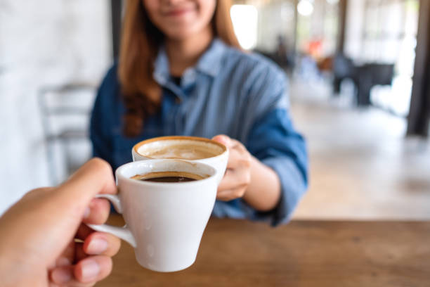 istock a woman and a man clinking coffee cups together in cafe 1319906451