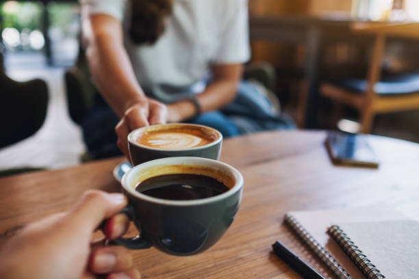 istock a man and a woman clinking white coffee mugs in cafe 1319906457