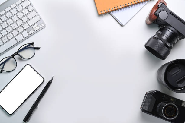 istock Top view smart phone, glasses, notebook and camera accessories on photographer workspace. 1319910446