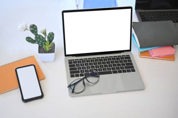 istock Mock up laptop computer, smart phone, cactus and notebook on white office desk. 1319910448