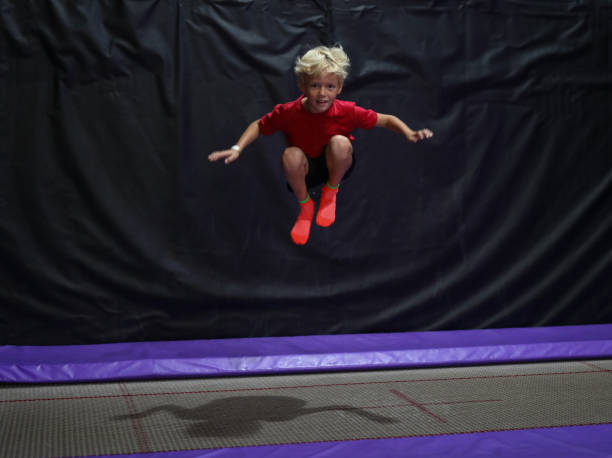 A young boy is jumping in a indoor trampoline play area. stock photo