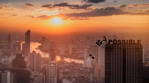Silhouette man pushing letters I and M from the rock. Word 'possible' standing sound. Sunrise sky at city scape background. Concept of opportunity,copy space. Silhouette man pushing letters I and M from the rock. Word 'possible' standing sound. Sunrise sky at city scape background. Concept of opportunity,copy space. impossible possible stock pictures, royalty-free photos & images
