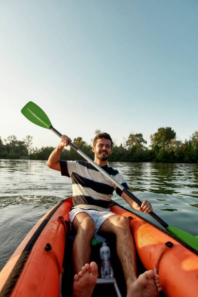 istock Active young man looking cheerful while kayaking in a lake, surrounded by peaceful nature on a summer afternoon 1319916499