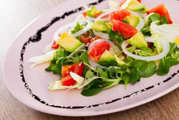 Vitamin salad from avocado, tomatoes, grapefruit and fresh cornsalad in white plate
