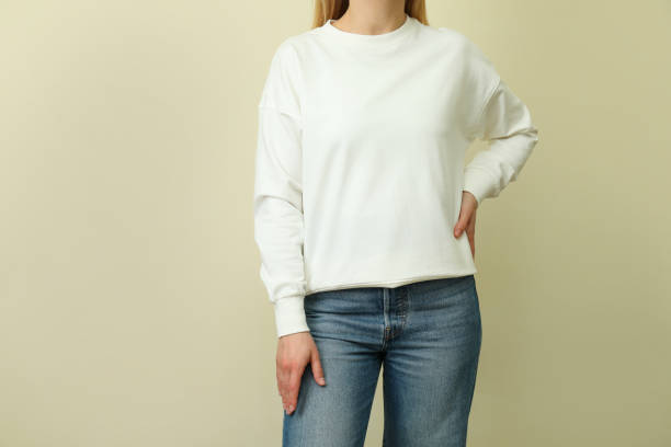 istock Young woman in white sweatshirt against beige background 1319920395
