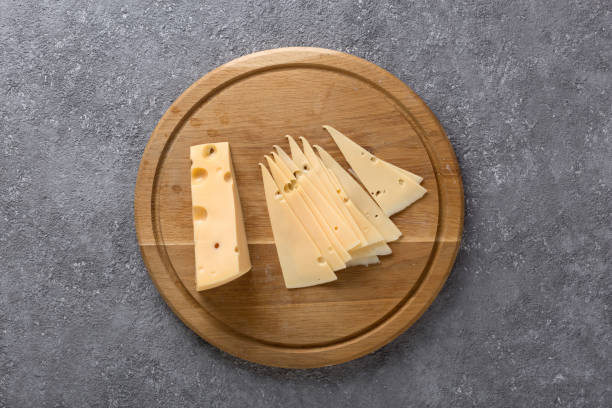 Piece of cheese and slices on a kitchen board close up