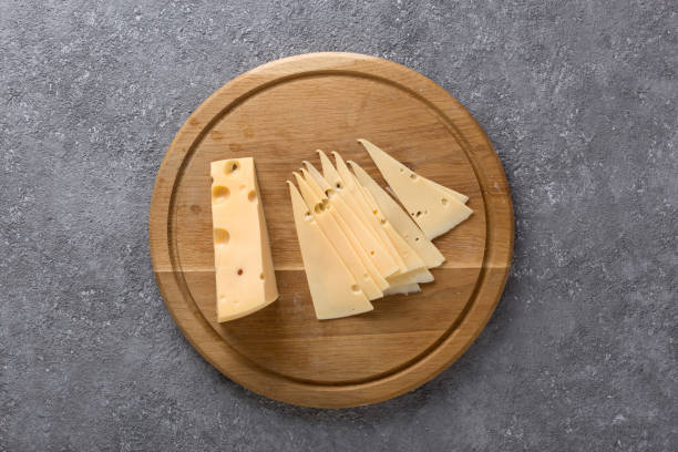 Piece of cheese and slices on a kitchen board close up stock photo