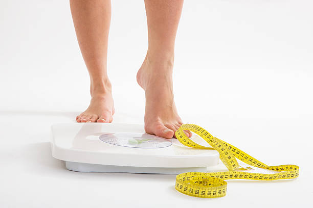 Diet Woman stepping on scale, canon 1Ds mark III weight scale photos stock pictures, royalty-free photos & images