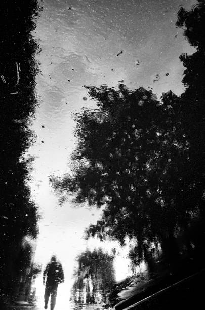 istock Inverted reflection in a puddle of a passer-by walking down the street 1319923729
