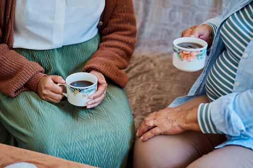 istock Shot of an unrecognisable young woman having coffee with her elderly relative on the sofa at home 1319926341