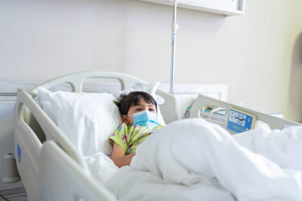 Little child patient with protective face mask lying on bed at hospital Little child  patient with protective face mask lying on bed at hospital sick child hospital bed stock pictures, royalty-free photos & images