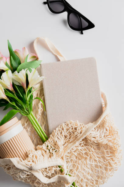 istock String bag with cup of coffee, flowers, paper notebook on white background. Elegant feminine accessories. Sustainable lifestyle concept. 1319927402