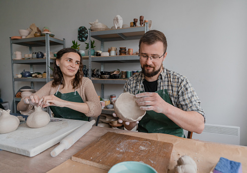 Young Caucasian man and woman ceramist working together in their studio