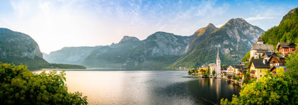 vue panoramique du vieux hallstatt de vieille ville célèbre et du lac bleu profond alpin avec le bateau de touriste dans la lumière d’or scénique de matin sur une belle journée ensoleillée au lever du soleil en été, salzkammergut, autriche - upper austria photos et images de collection