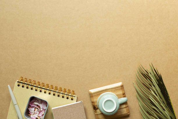 istock Notebook, pen, mug cup, green leaf on kraft brown paper background. flat lay, top view, copy space 1319934053