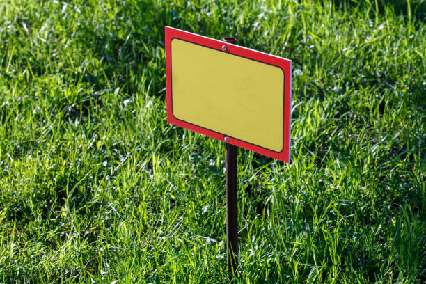 istock blank yellow sign mockup on green lawn background - close-up with selective focus 1319935082