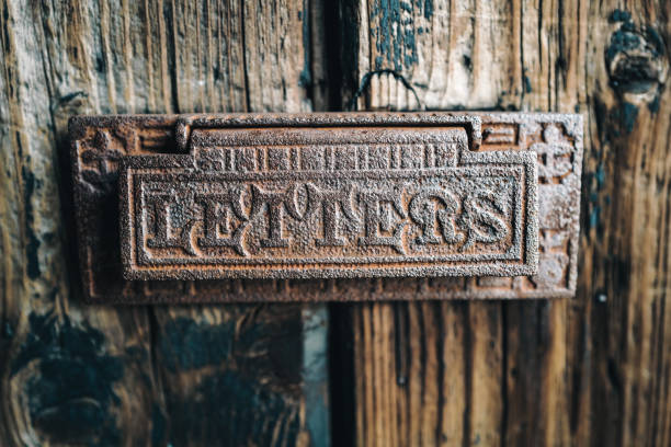 Old fashioned metal mailbox on an old oak wooden door. The mailbox is weathered and rusty.